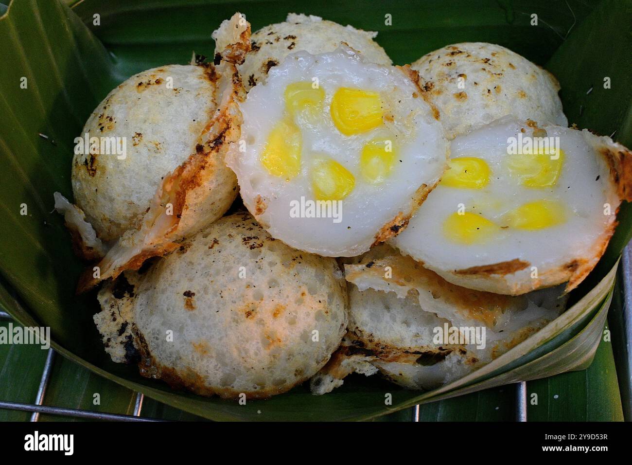 Pancake Khanom Krok con ripieni di mais, un popolare dessert tailandese di Street food a base di farina di riso, latte di cocco, cucinato con fragranti foglie di pandan Foto Stock