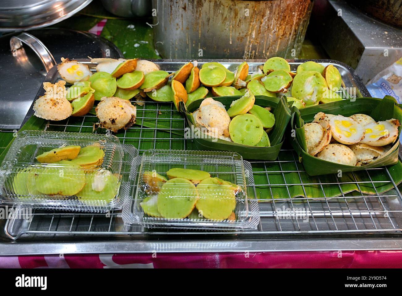 Pancake Khanom Krok assortiti, un dolce e gommoso dessert tailandese a base di farina, latte di cocco e foglie di pandano, in vendita presso uno stand di Street food Foto Stock