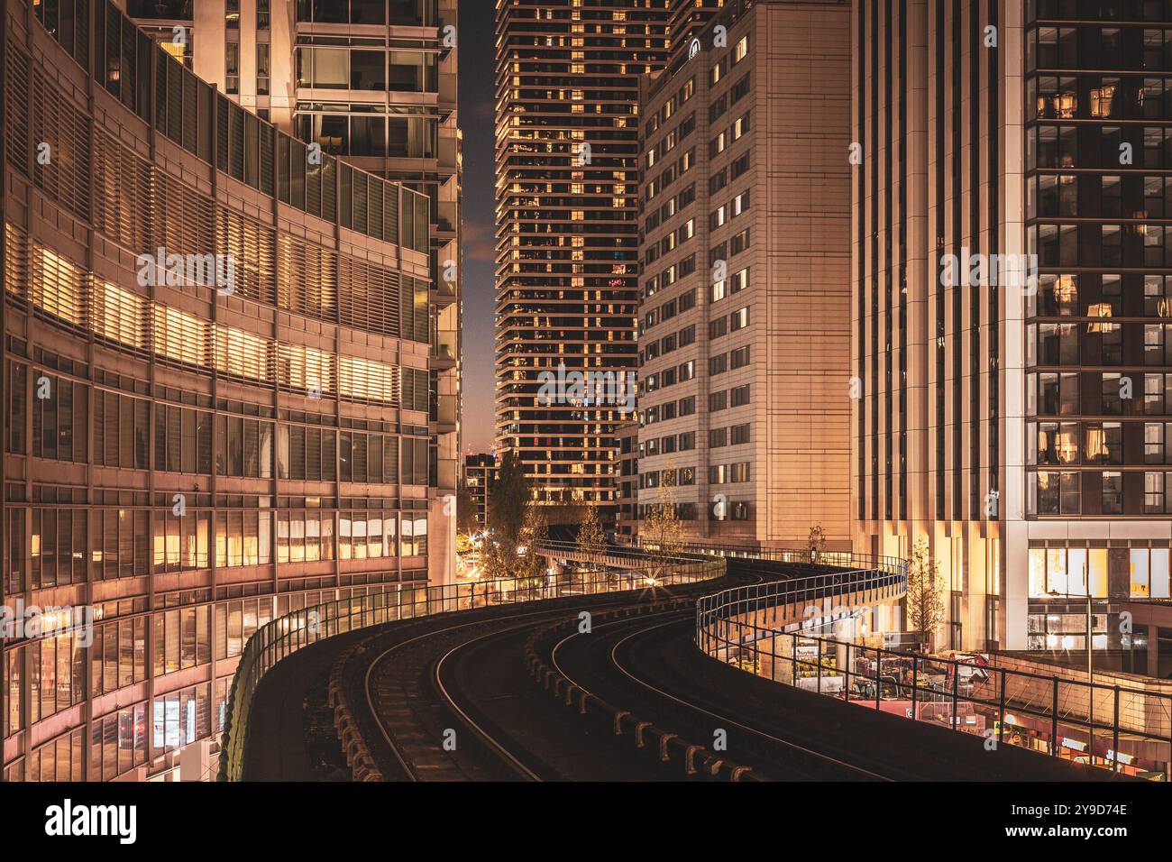 Vista notturna della stazione DLR di Canary Wharf, caratterizzata da un'architettura moderna, grattacieli illuminati e l'iconica ferrovia sopraelevata curva. Foto Stock