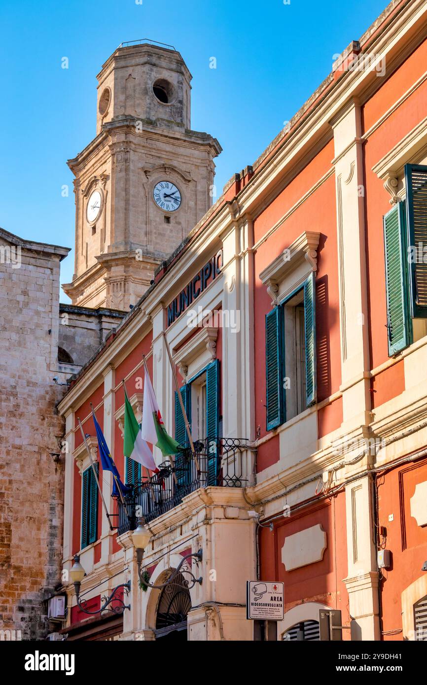 La facciata del Municipio di Monopoli, situato nel centro storico di Monopoli, Puglia, Italia, con la torre dell'orologio della Chiesa di San Francesc Foto Stock