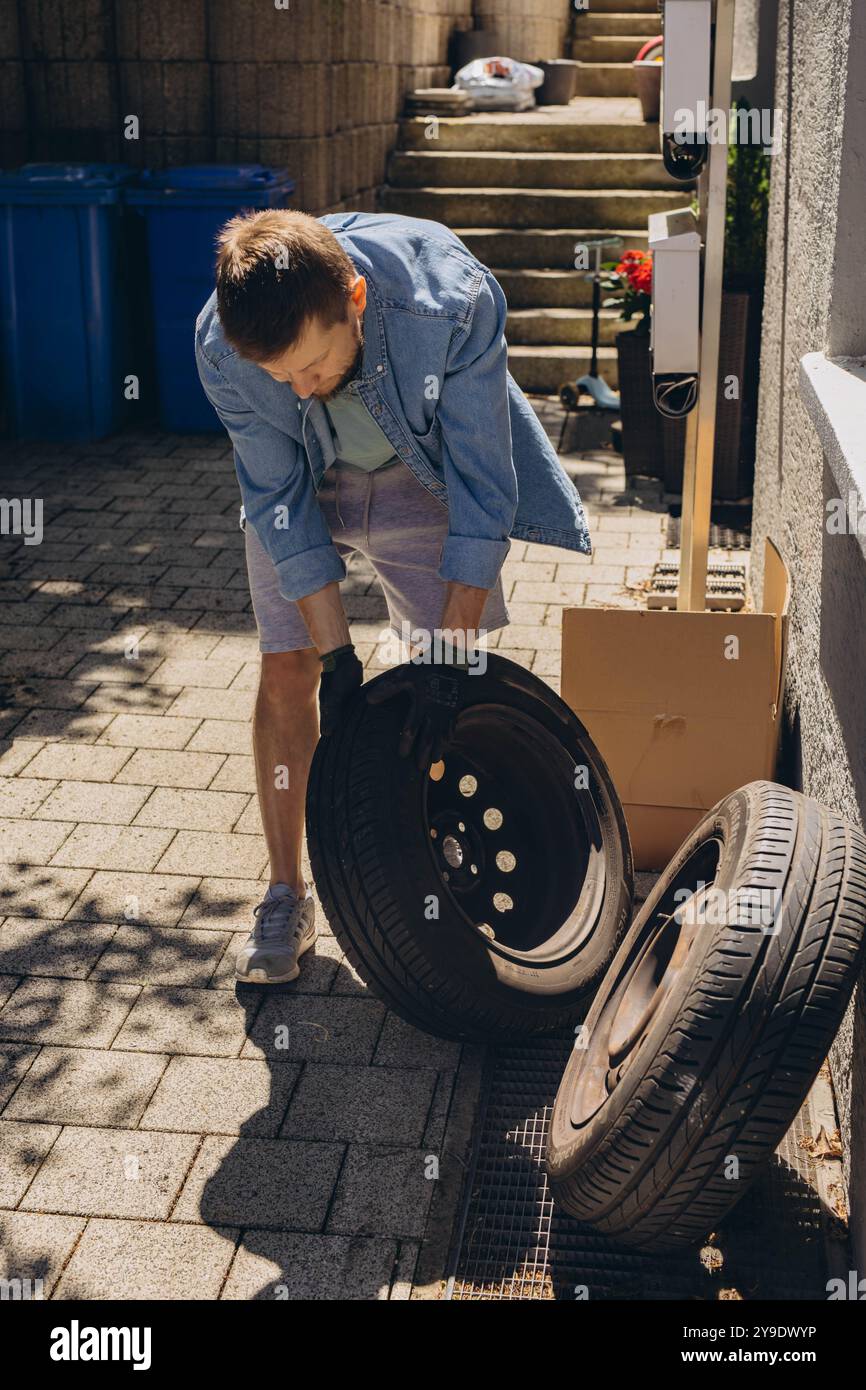 Giovane uomo che svita i dadi di fissaggio sulla ruota dell'auto in fase di sostituzione dei nuovi pneumatici, utilizzando la chiave durante la sostituzione dello pneumatico forato su strada. Foto di alta qualità Foto Stock