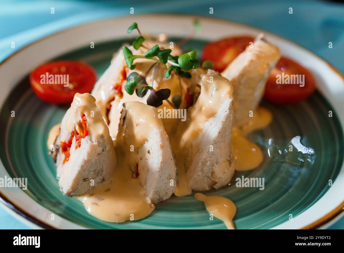 Squisita Roulade di pollo gourmet con salsa cremosa e contorno di pomodoro fresco. Foto Stock