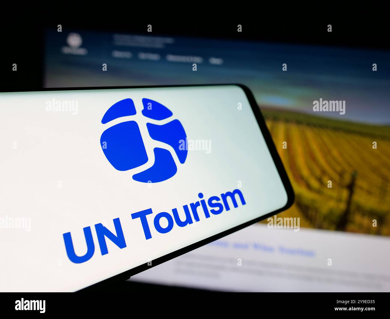Cellulare con logo dell'agenzia delle Nazioni Unite per il turismo delle Nazioni Unite sullo schermo davanti al sito web. Messa a fuoco al centro del display del telefono. Foto Stock