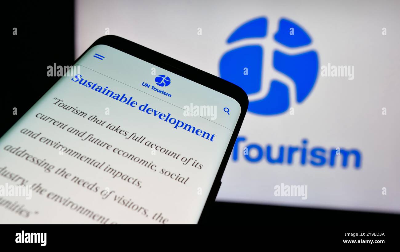 Telefono cellulare con sito web dell'agenzia delle Nazioni Unite per il turismo delle Nazioni Unite sullo schermo davanti al logo. Mettere a fuoco in alto a sinistra sul display del telefono. Foto Stock