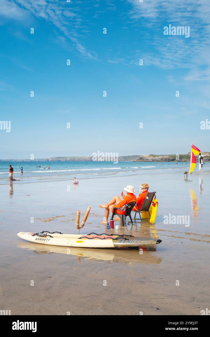 Due bagnini RNLI seduti sulle sedie durante il servizio osservano i turisti in mare con la bassa marea sulla GT Great Western Beach a Newquay in Cornovaglia nel Regno Unito Foto Stock