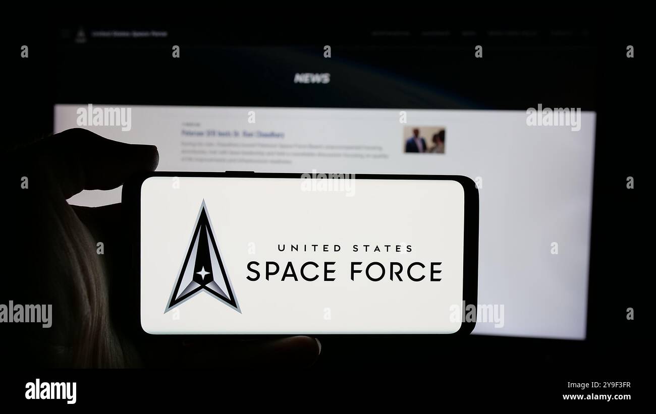 Persona che tiene un cellulare con il logo della United States Space Force (USSF) sullo schermo davanti alla pagina web. Mettere a fuoco il display del telefono. Foto Stock