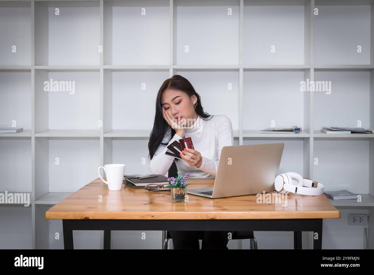 Stressante donna d'affari asiatica con un enorme debito di carte di credito. Foto Stock