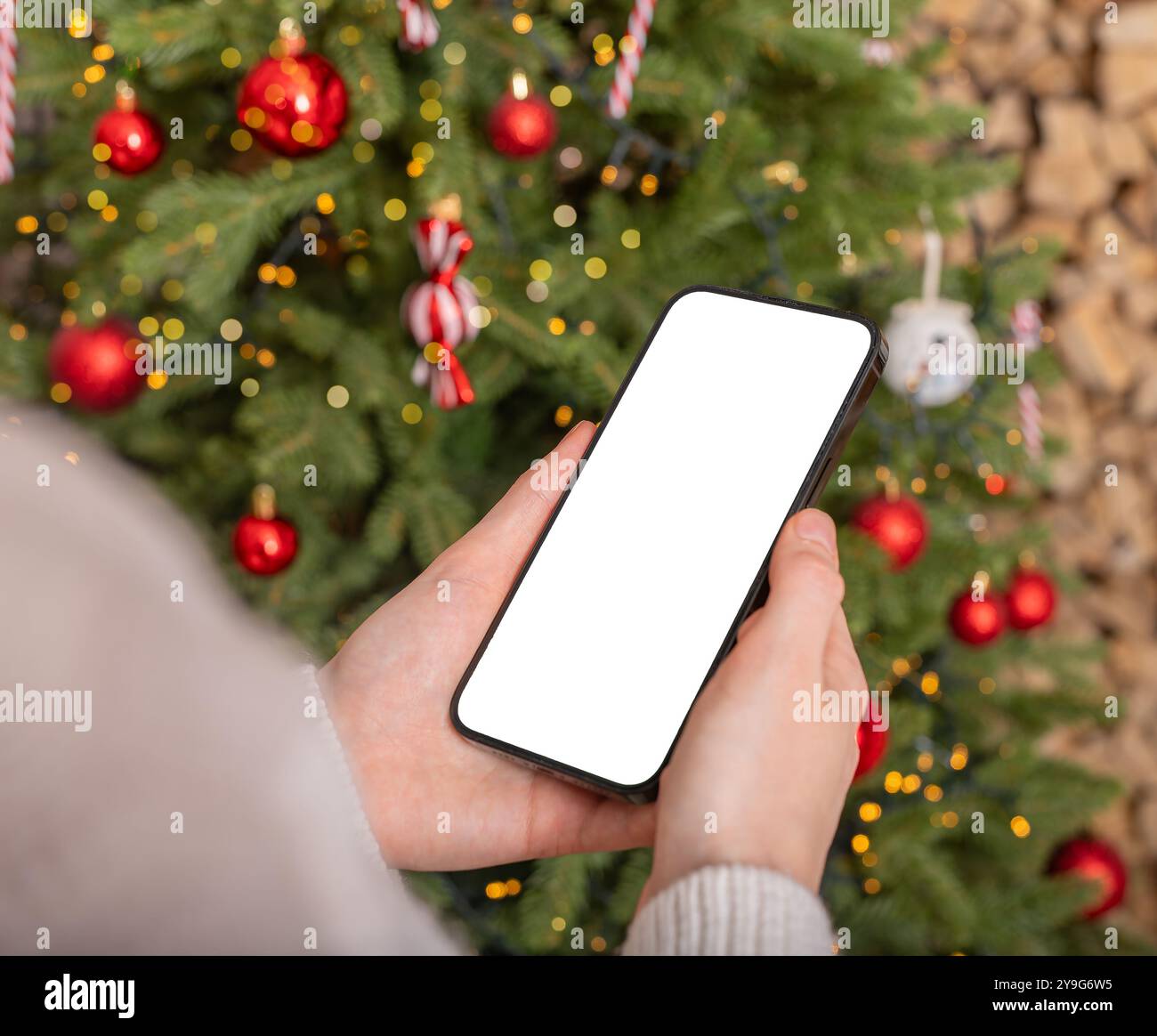 Con la mano che regge il mockup dello schermo del telefono cellulare, lo smartphone, le vacanze di Natale e la tecnologia. Foto Stock