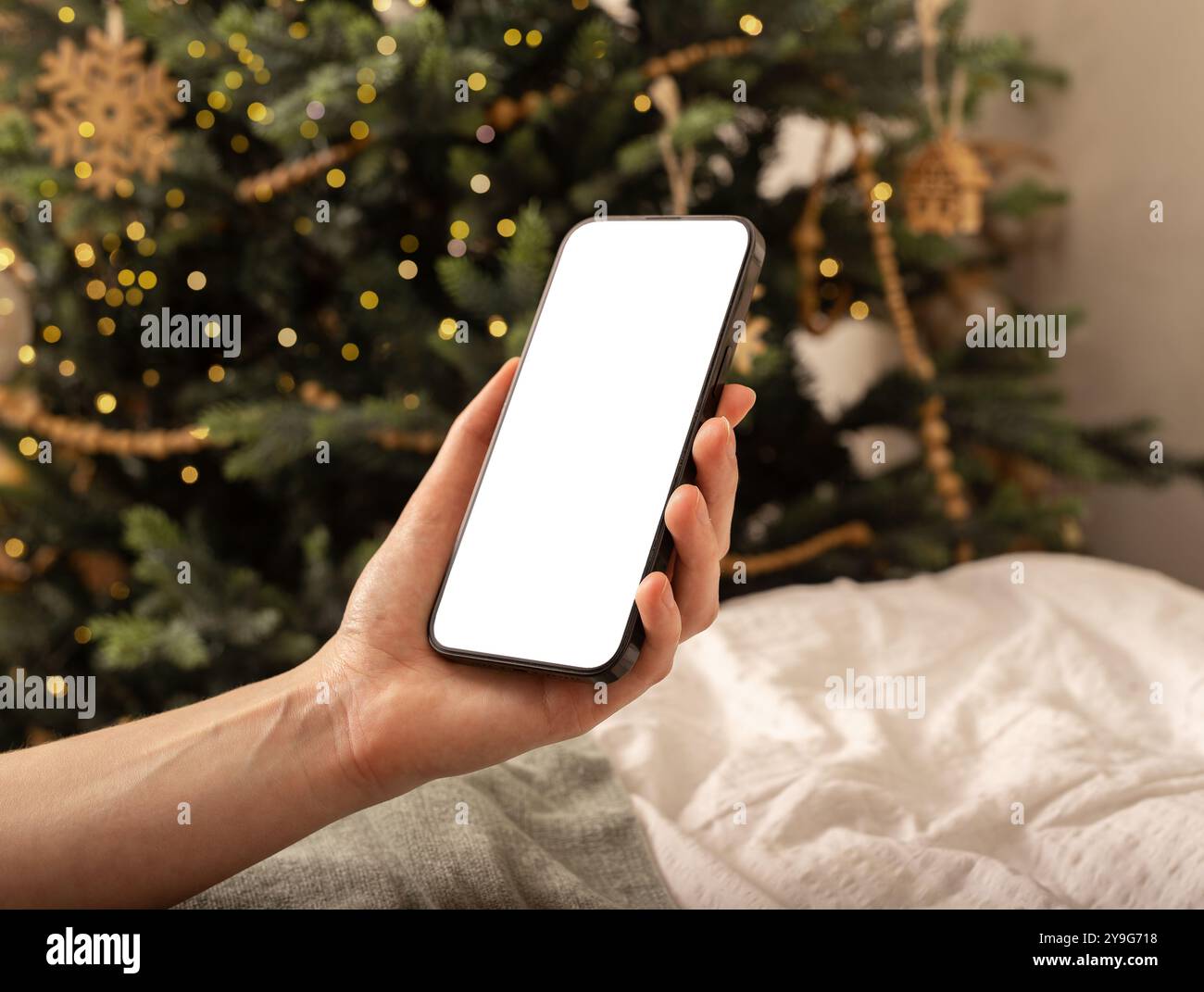 Con la mano che regge il mockup dello schermo del telefono cellulare, lo smartphone, le vacanze di Natale e la tecnologia. Foto Stock