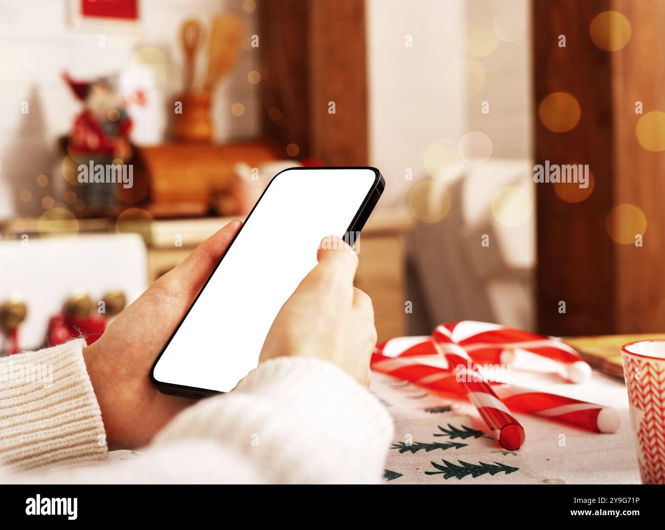 Con la mano che regge il mockup dello schermo del telefono cellulare, lo smartphone, le vacanze di Natale e la tecnologia. Foto Stock