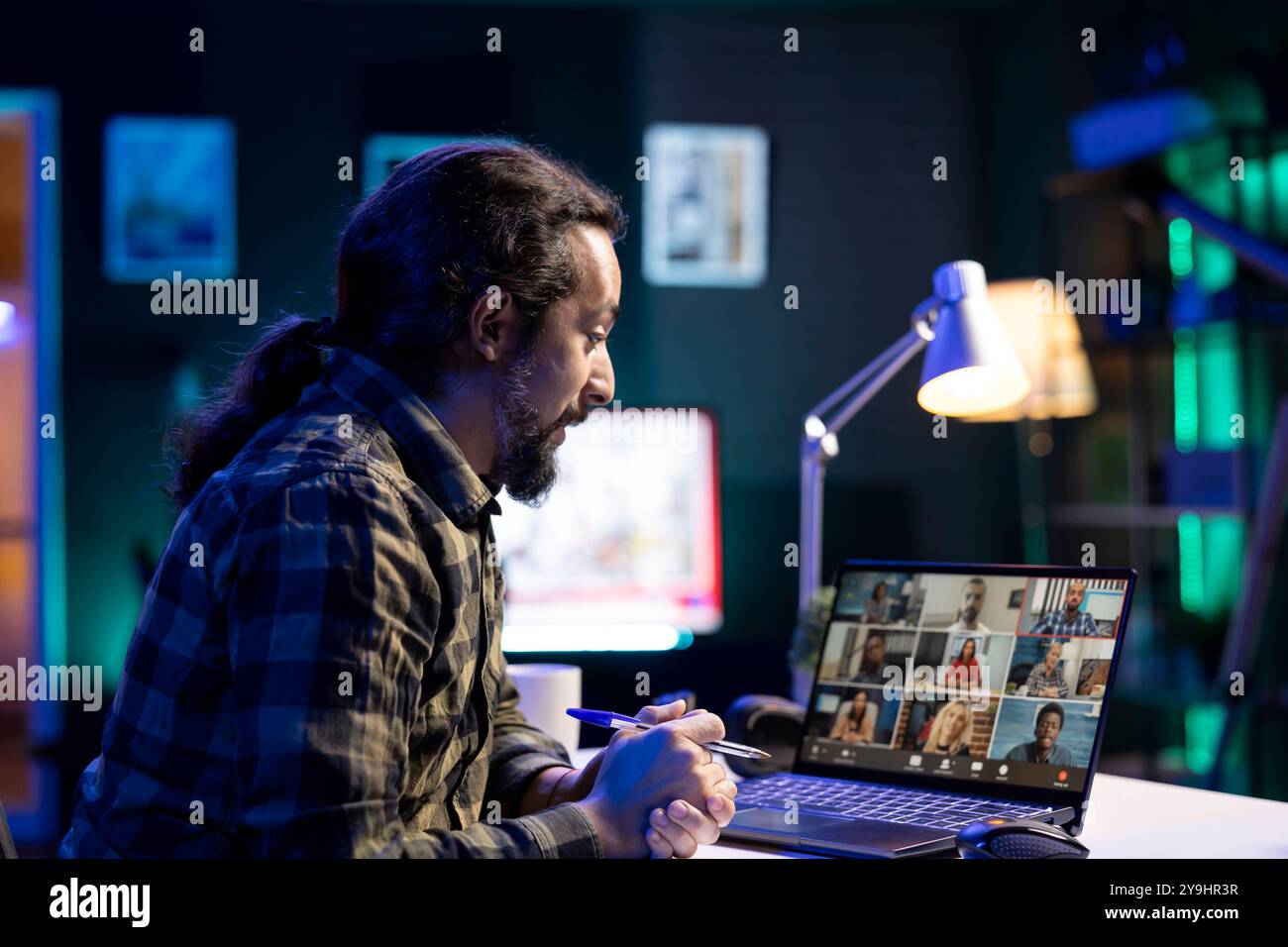 Un uomo con la barba sta confrontando documenti con un gruppo di persone di diversa provenienza in una riunione virtuale. Persona di sesso maschile che partecipa a una videoconferenza sul proprio laptop digitale. Foto Stock