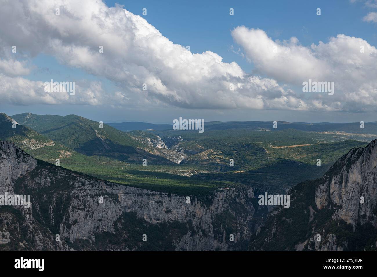 Scogliere e grotte verdeggianti della gola del Verdon in Francia, con la luce del sole che accentua le formazioni geologiche e le ombre contrastanti Foto Stock