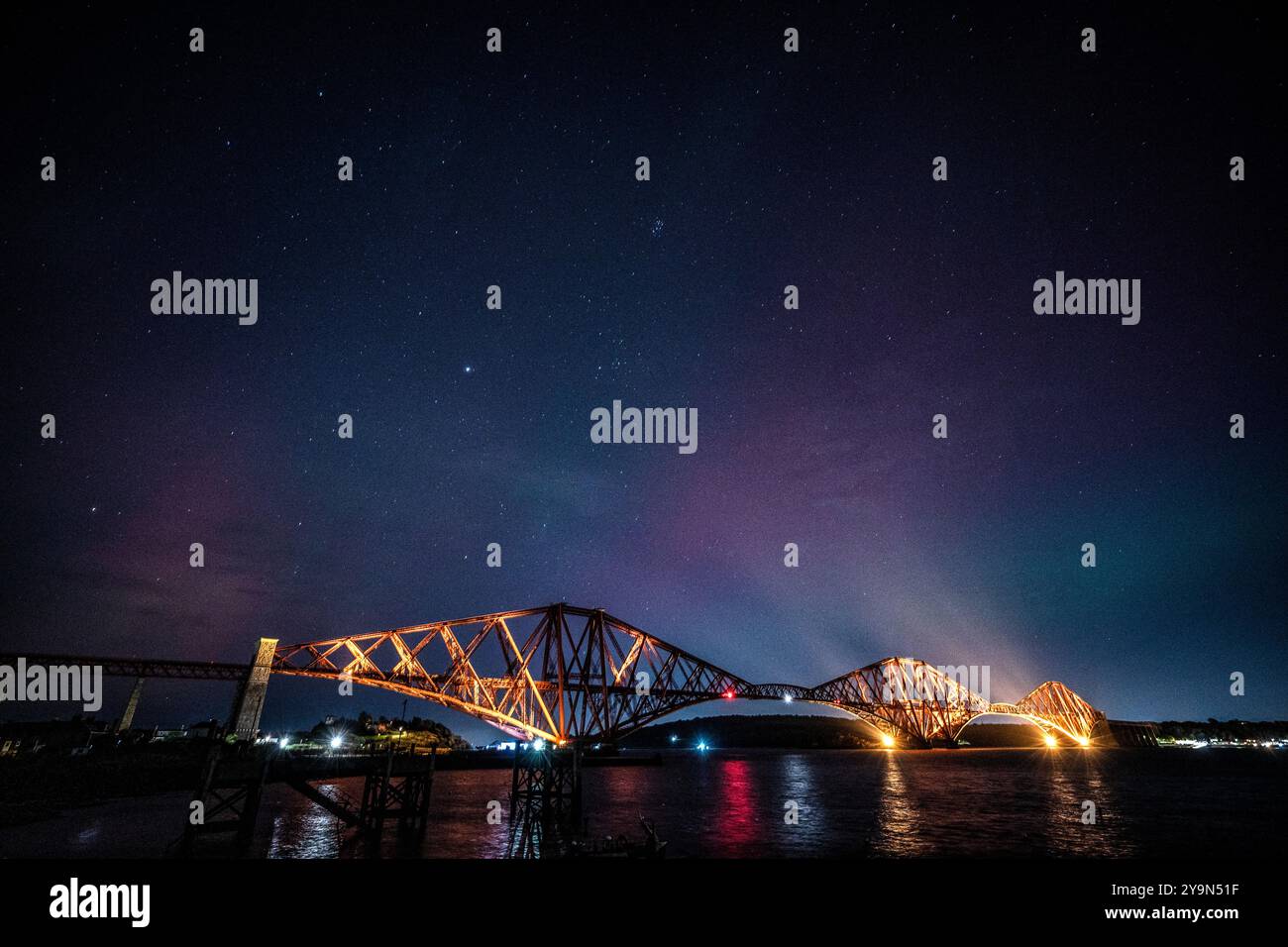 L'aurora boreale, conosciuta anche come aurora boreale, è esposta nei cieli sopra il Forth Bridge, North Queensferry a Fife. I display Aurora si verificano quando particelle cariche urtano contro i gas nell'atmosfera terrestre intorno ai poli magnetici. Quando si scontrano, la luce viene emessa a varie lunghezze d'onda, creando delle colorate esposizioni nel cielo. Data foto: Venerdì 11 ottobre 2024. Foto Stock