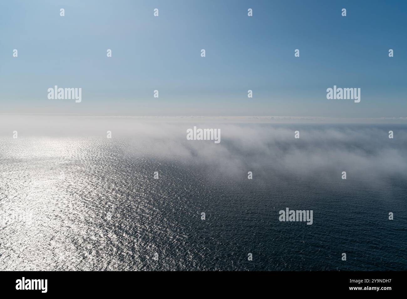 Una morbida nebbia sorge dall'oceano mentre il sole inizia ad illuminare l'orizzonte. Foto Stock