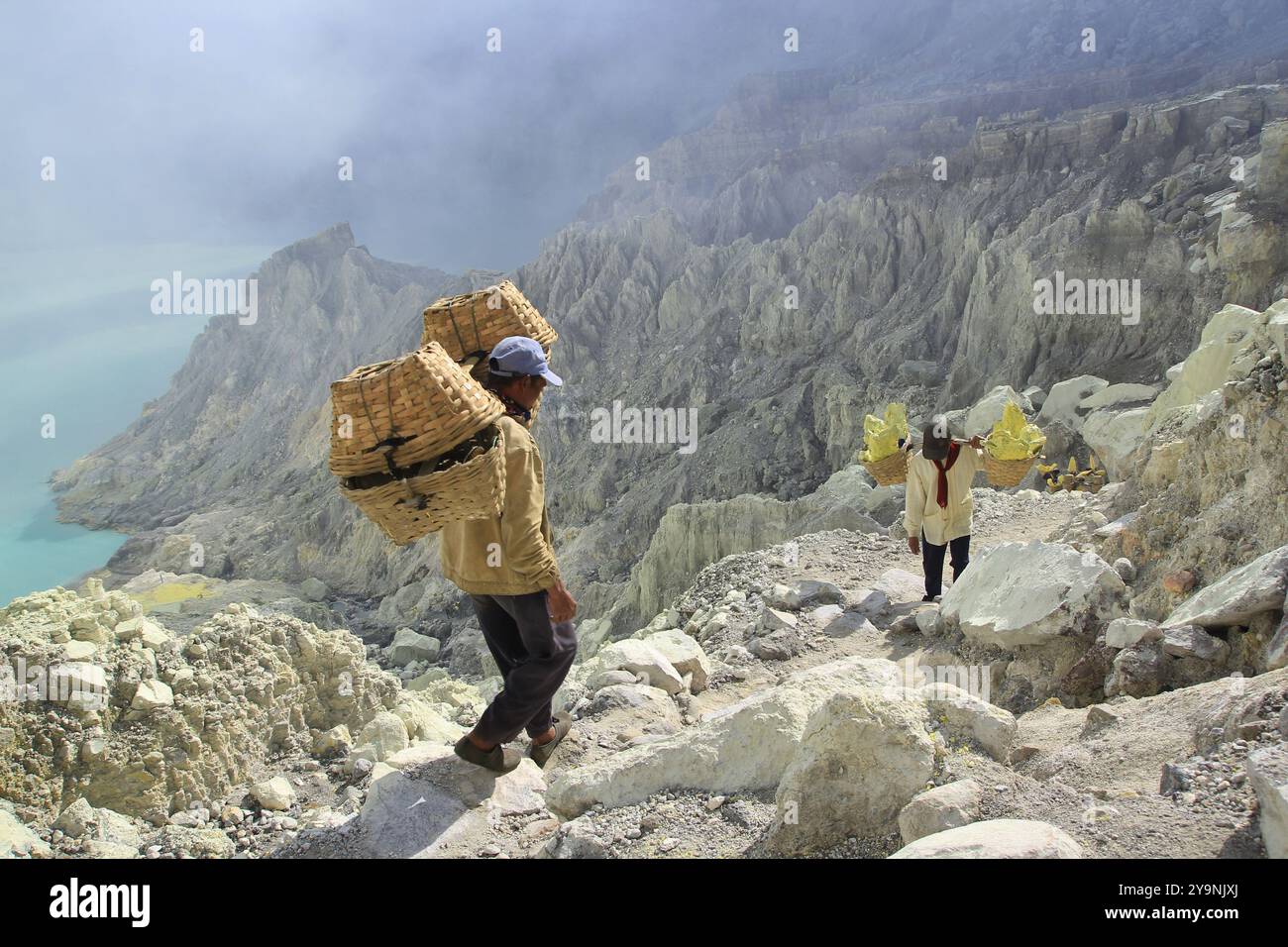 I minatori di zolfo si arrampicano sulle pareti della caldera del cratere Ijen con un carico medio di 90 kg. Foto Stock