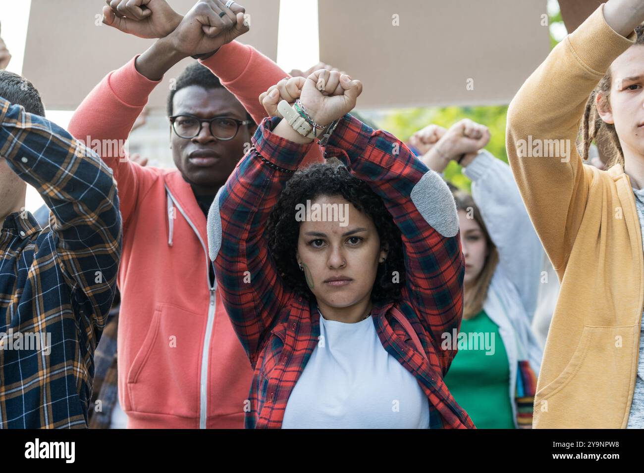 Gruppo di giovani diversi che alzano i pugni in solidarietà durante una protesta. L'immagine cattura l'empowerment dei giovani, l'unità nella diversità e la passione per i soci Foto Stock