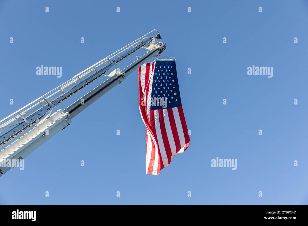 Bandiera americana appesa a un camion dei pompieri nel cielo Foto Stock