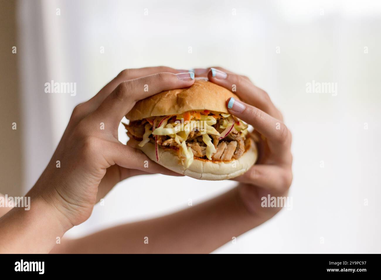Mani che raccolgono hamburger con carne e spada Foto Stock