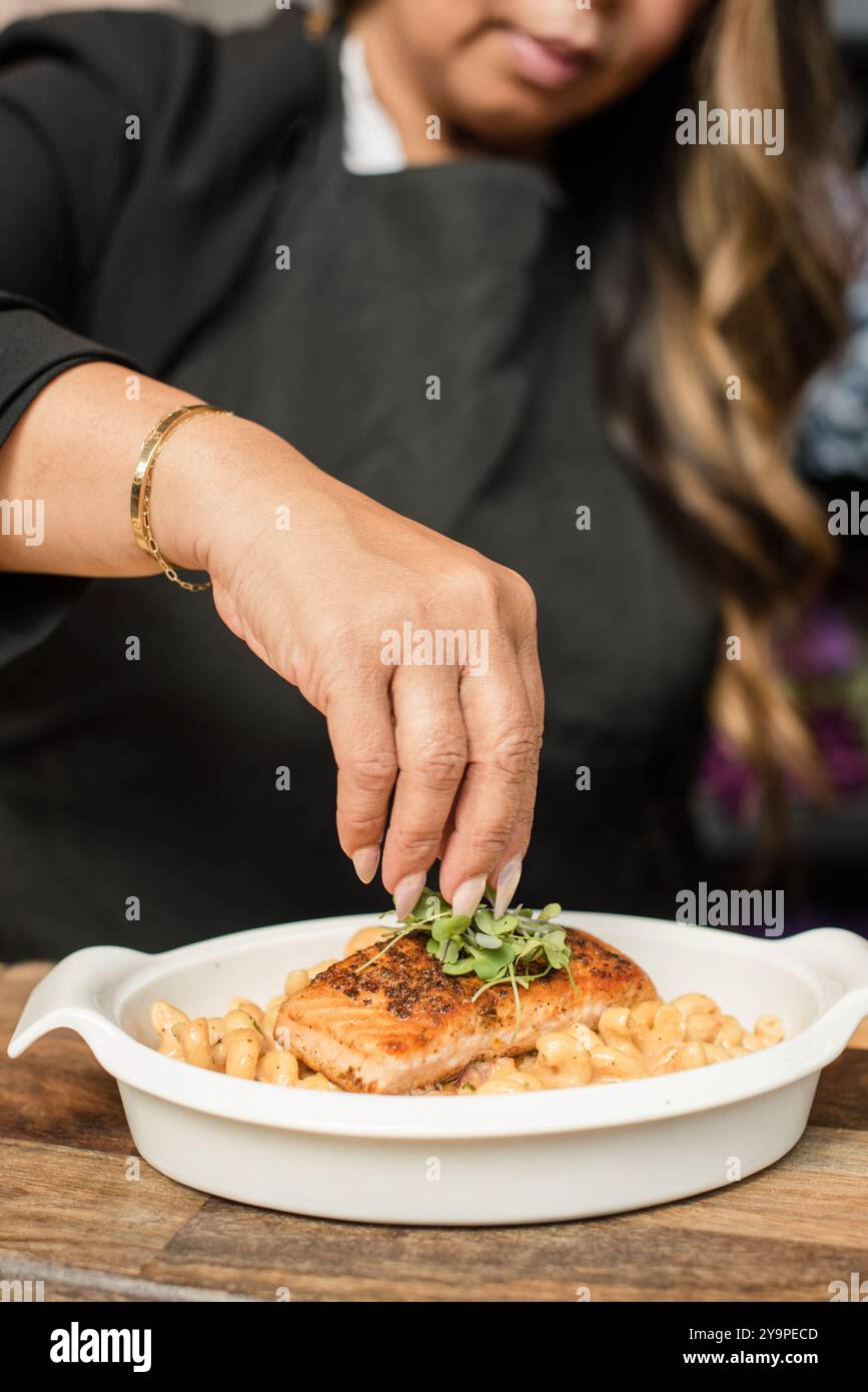 Chef donna che garnisce salmone e formaggio mac n Foto Stock