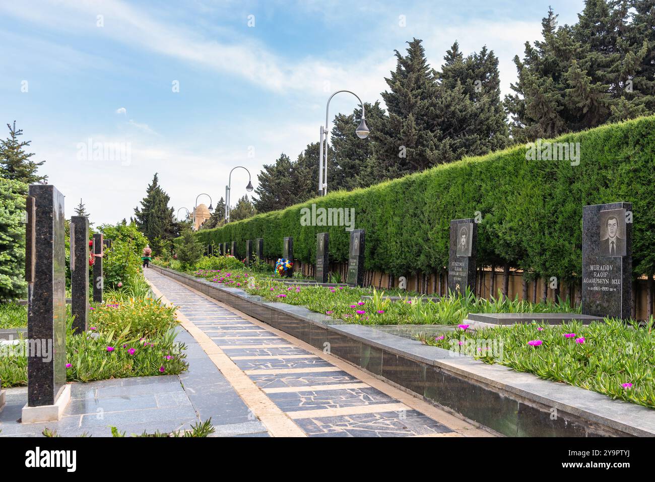 Baku, Azerbaigian - 6 maggio 2024: Vicolo dei Martiri, abbellito da ritratti commemorativi tra alberi verdeggianti e un'atmosfera serena Foto Stock