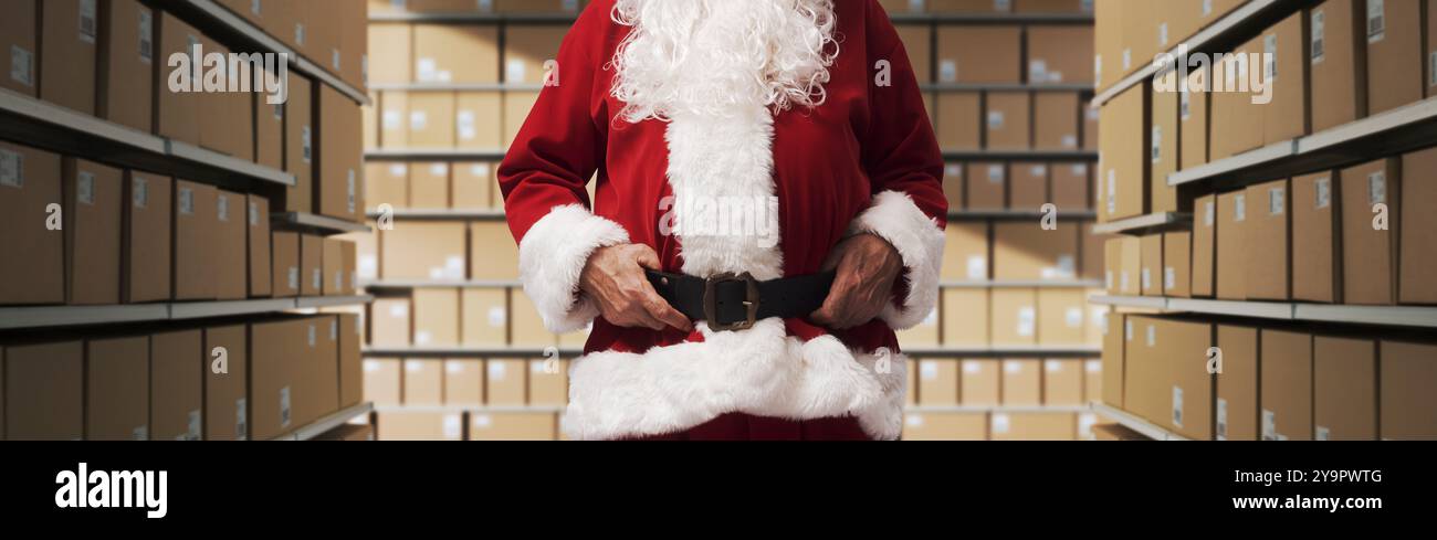 Babbo Natale in piedi nel corridoio del magazzino e controllare le scatole di consegna con i regali di Natale Foto Stock