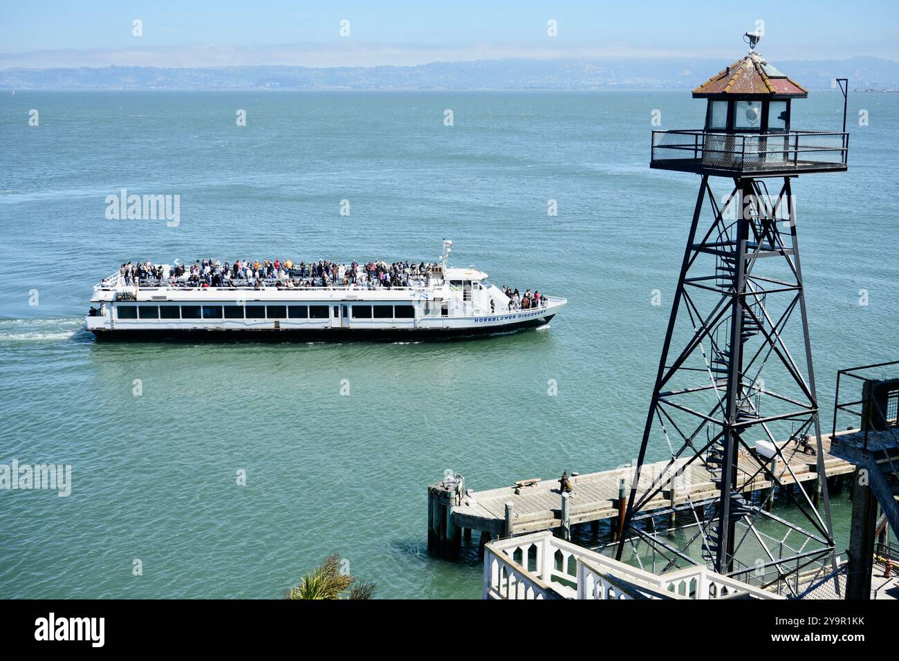 Nave passeggeri Hornblower Discovery che arriva all'isola di Alcatraz sotto la torre di guardia. Foto Stock