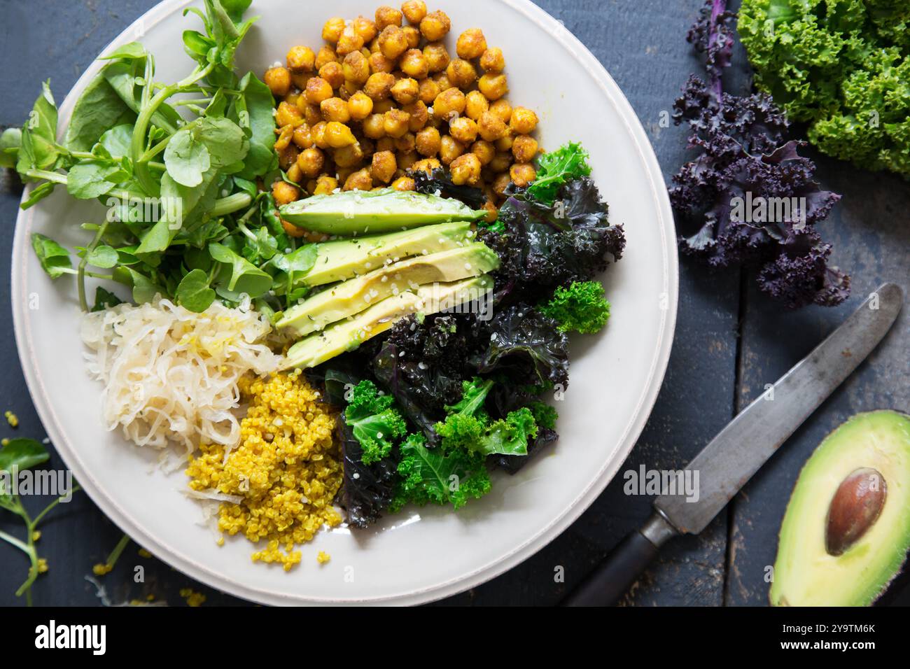 Insalata sana con quinoa, crauti, ceci piccanti, avocado e cavolo al vapore. Immagine di posizionamento piatto su piastra grigia chiara su sfondo blu scuro. Foto Stock