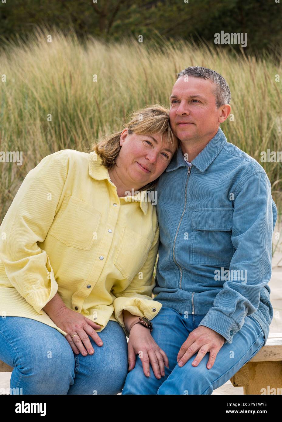 Felice coppia adulta innamorata seduta sulla panchina sulla spiaggia. L'uomo e la donna si abbracciano teneramente. Relazioni familiari Foto Stock