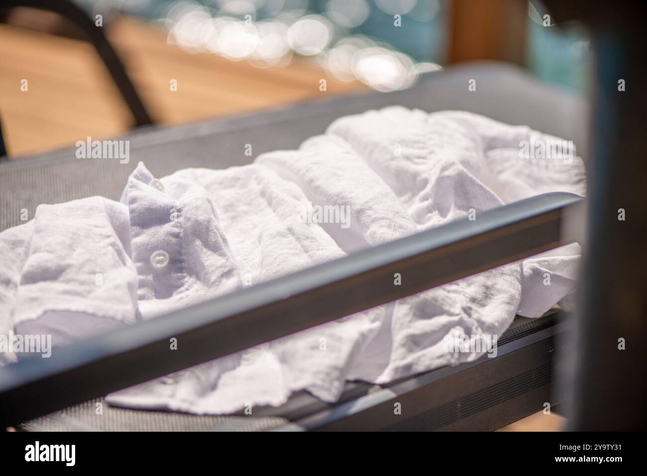 Una t-shirt bianca fresca drappeggiata in modo informale su un lettino, che cattura l'essenza di una giornata in spiaggia rilassata e del relax estivo. Foto Stock