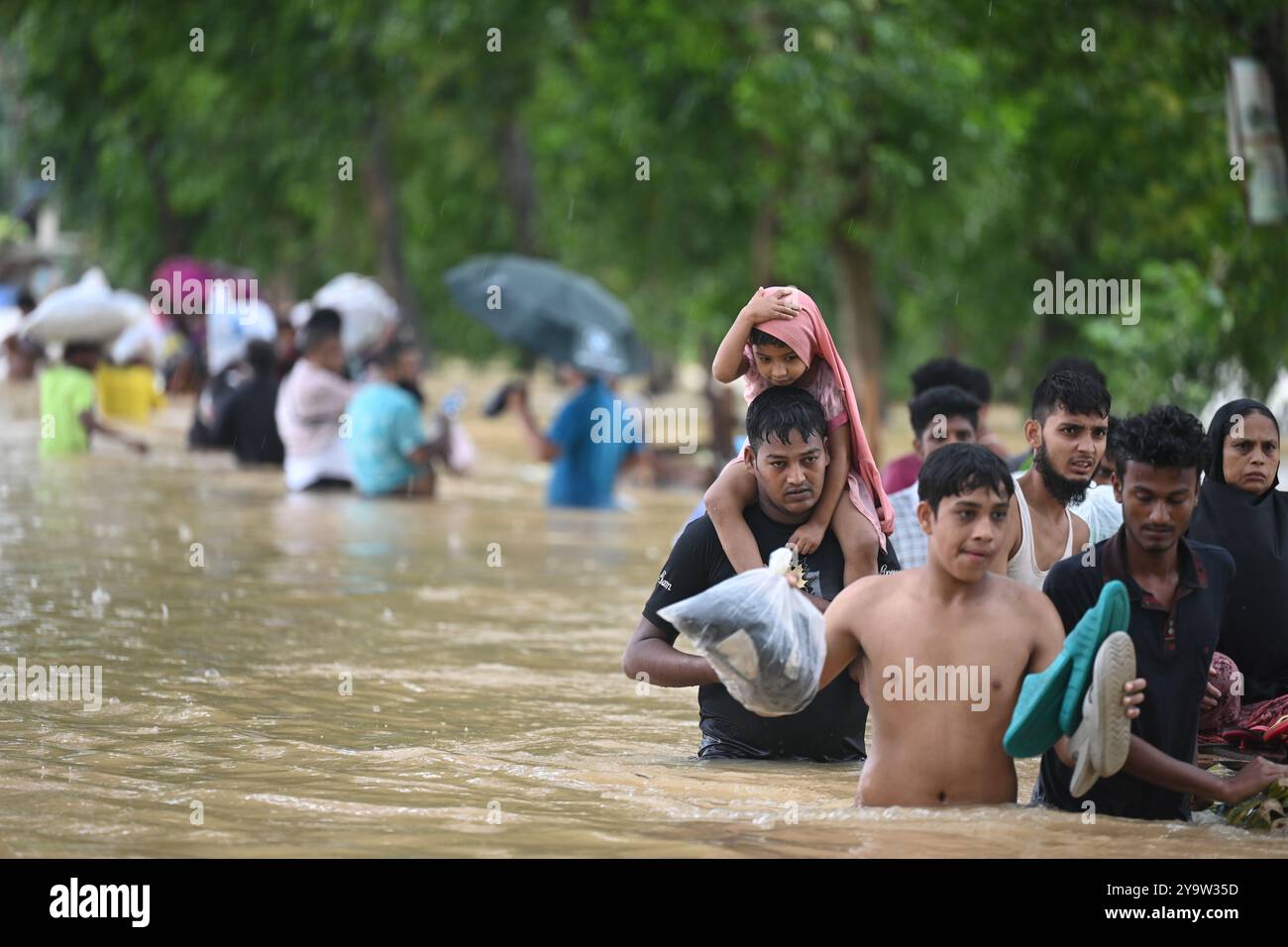 Le persone attraversano le acque alluvionali del distretto di Feni, Bangladesh, il 25 agosto 2024. Foto Stock