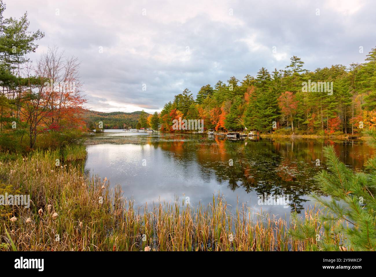 Le barche ormeggiavano lungo le rive boscose di un lago di montagna durante la stagione dei colori autunnali Foto Stock
