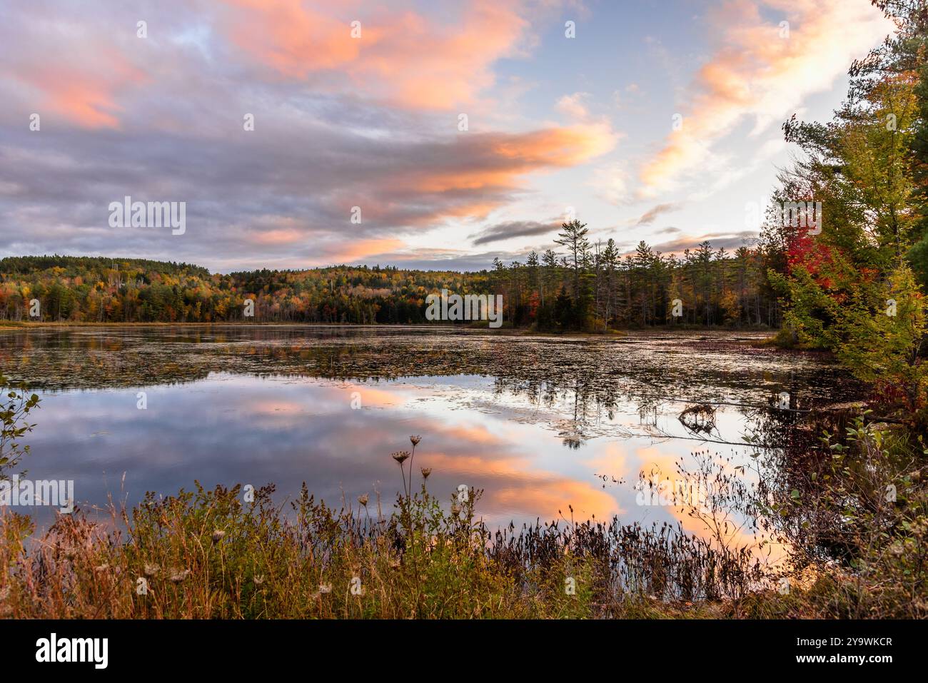 Cielo spettacolare su un lago di montagna con coste boscose al culmine dei colori autunnali al tramonto Foto Stock
