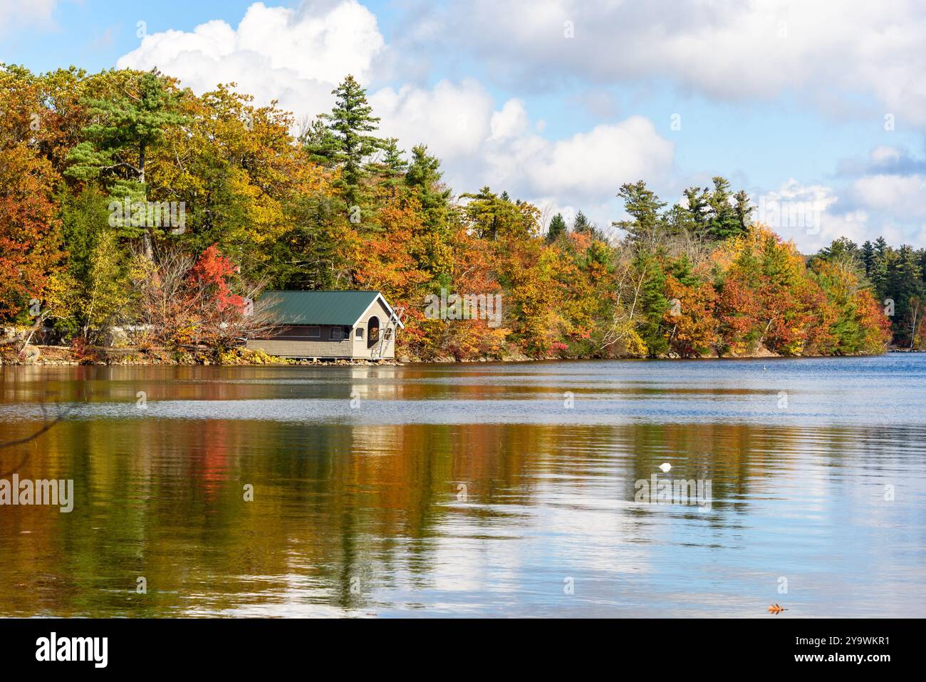 Boathouse in legno su un lago circondato da boschi in cima al fogliame autunnale in una giornata di sole Foto Stock