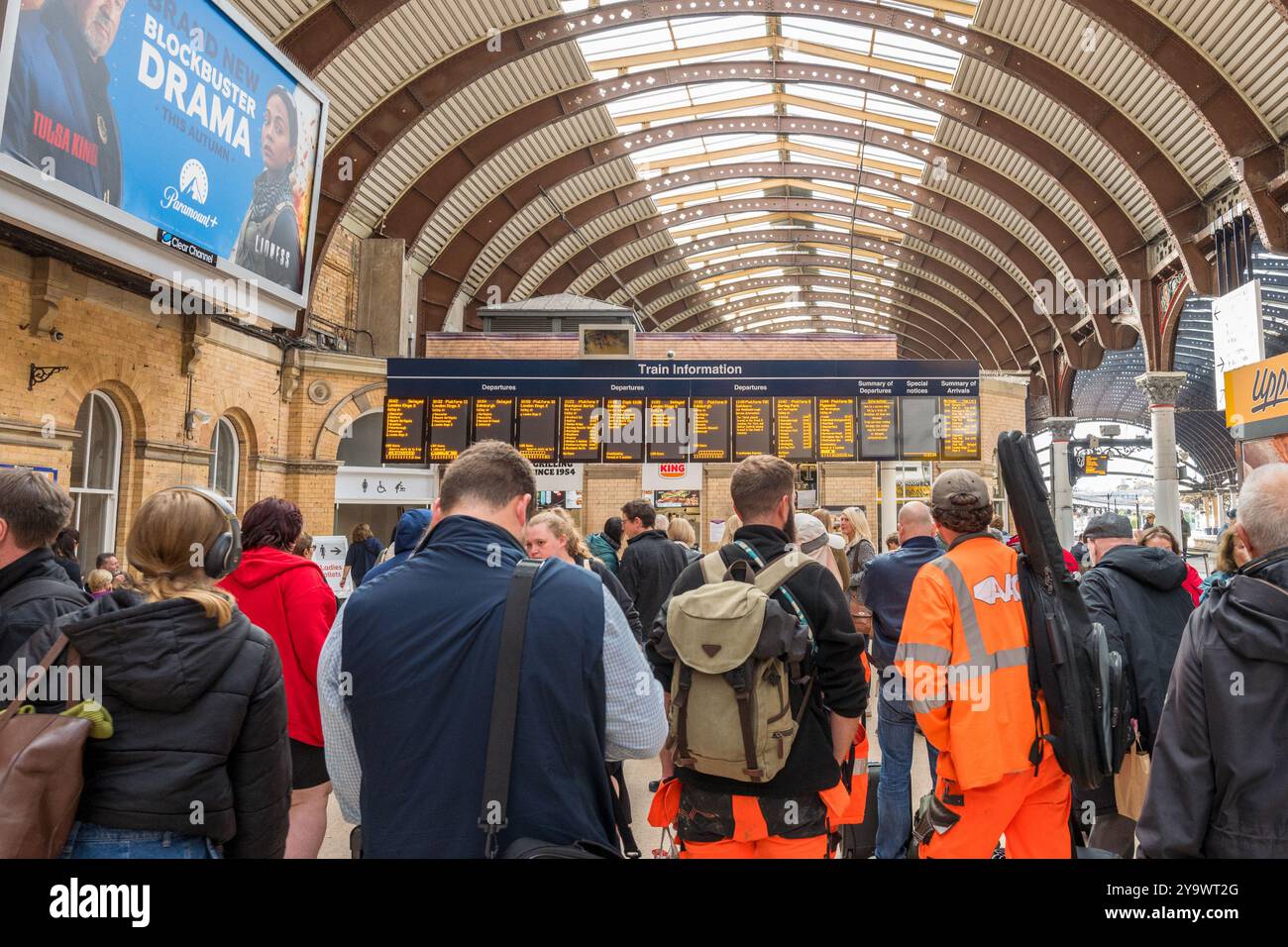 I passeggeri visualizzano l'orario del treno su un grande display elettronico alla stazione ferroviaria di york. Foto Stock
