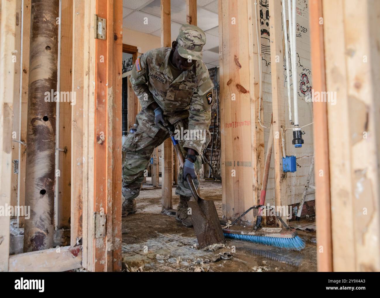 Marshall, Stati Uniti. 10 ottobre 2024. Peakpellem Laoukpessi, assegnato al 502nd Infantry Regiment, raschia il fango da un pavimento del magazzino danneggiato in seguito all'uragano Helene, 10 ottobre 2024 a Marshall, Carolina del Nord. Crediti: PFC. Cristian Lopez/US Army Photo/Alamy Live News Foto Stock