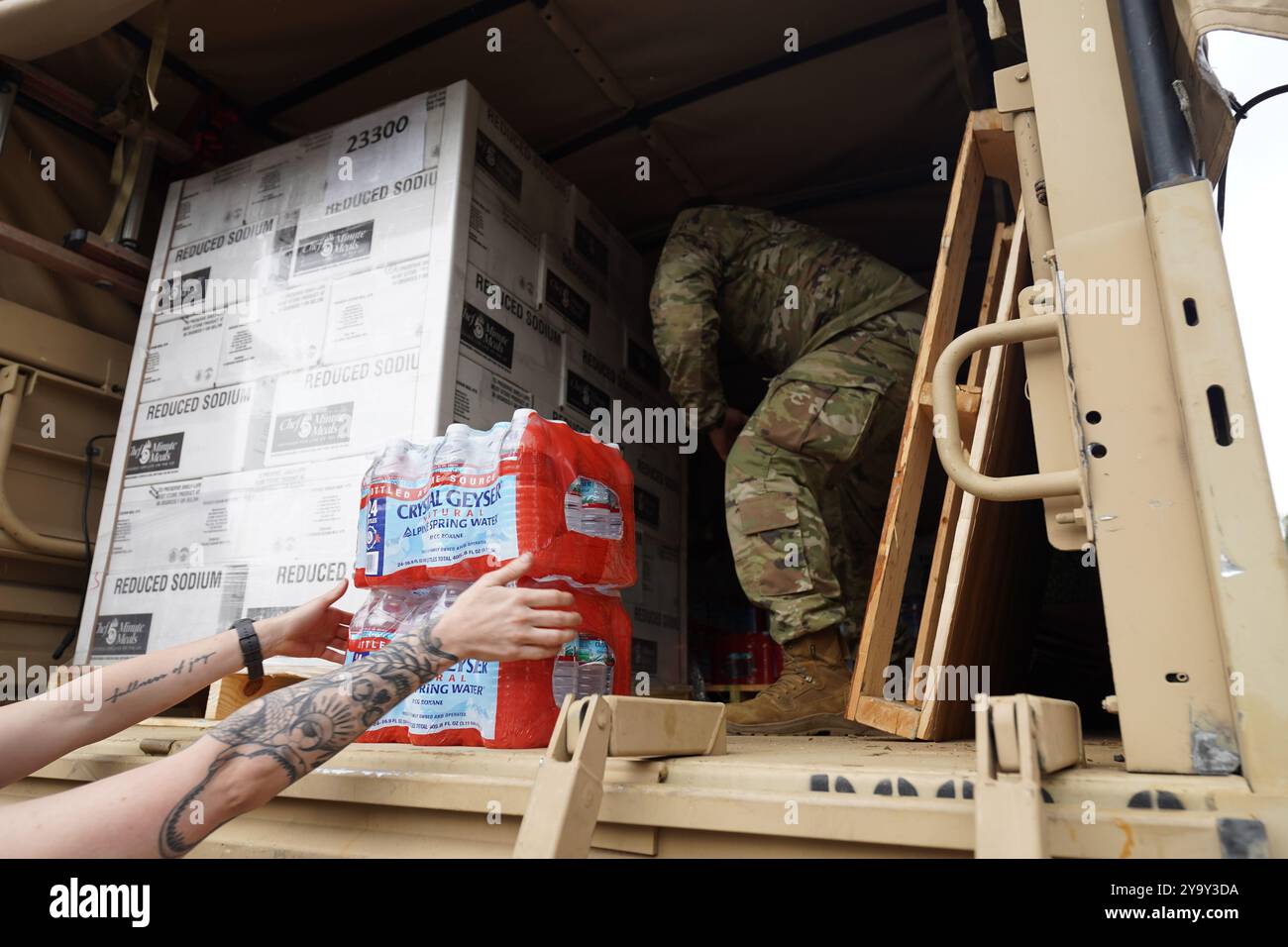 Hot Springs, Stati Uniti. 29 settembre 2024. I soldati dell'esercito americano con la Task Force Panther, insieme a volontari civili distribuiscono cibo e MREs ai sopravvissuti dopo l'uragano Helene alla William W. Estes Elementary School, il 30 settembre 2024 ad Asheville, Carolina del Nord. Crediti: Madeleine Cook/FEMA Photo/Alamy Live News Foto Stock