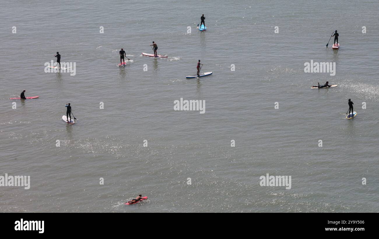 Sfondo naturale. Vista mare con la silhouette di un gruppo di persone in mare da lontano, con tavole da surf che fanno il pagaietto Foto Stock