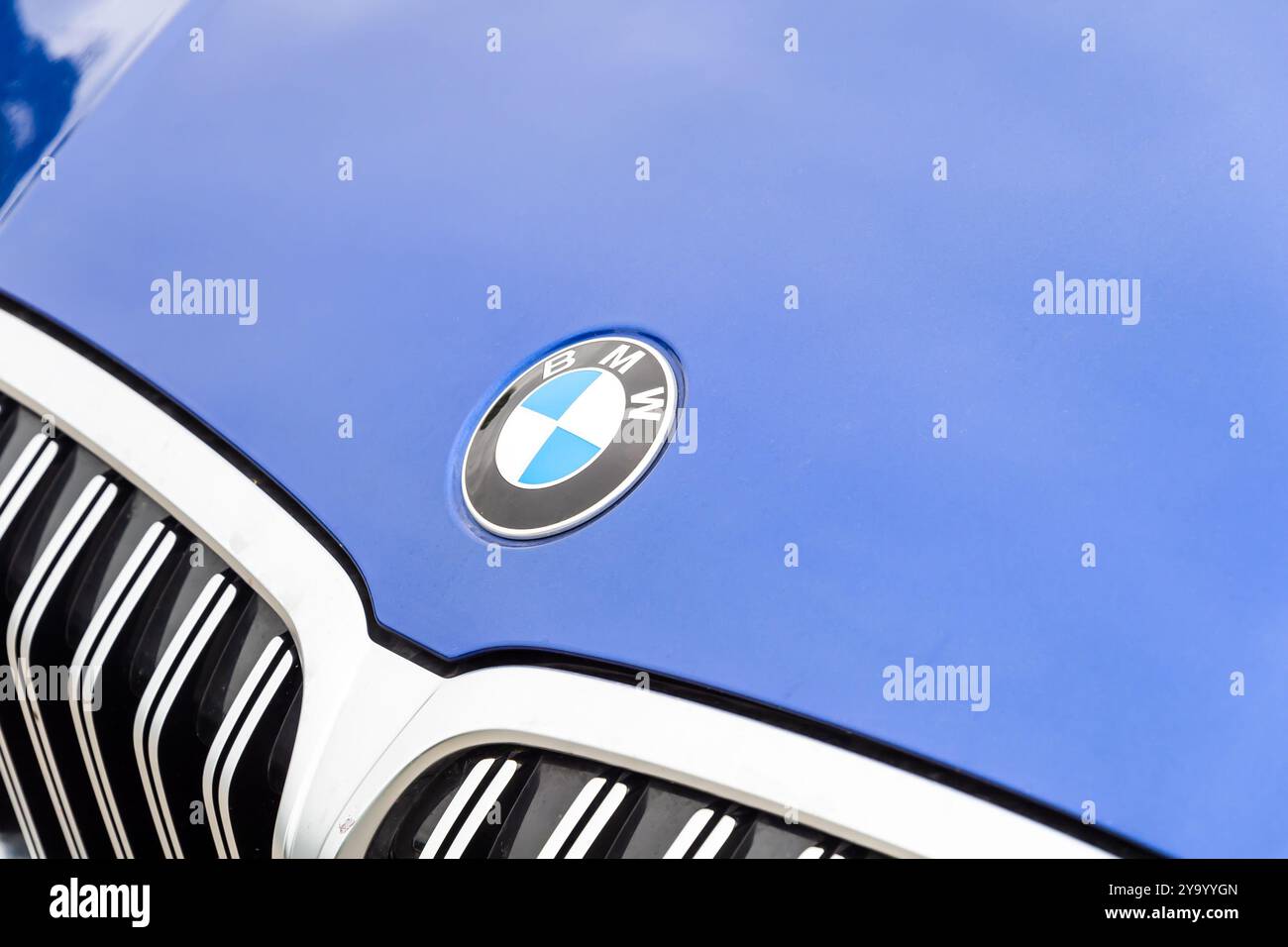 Il logo BMW su un'auto blu parcheggiata in un parcheggio pubblico. Foto Stock