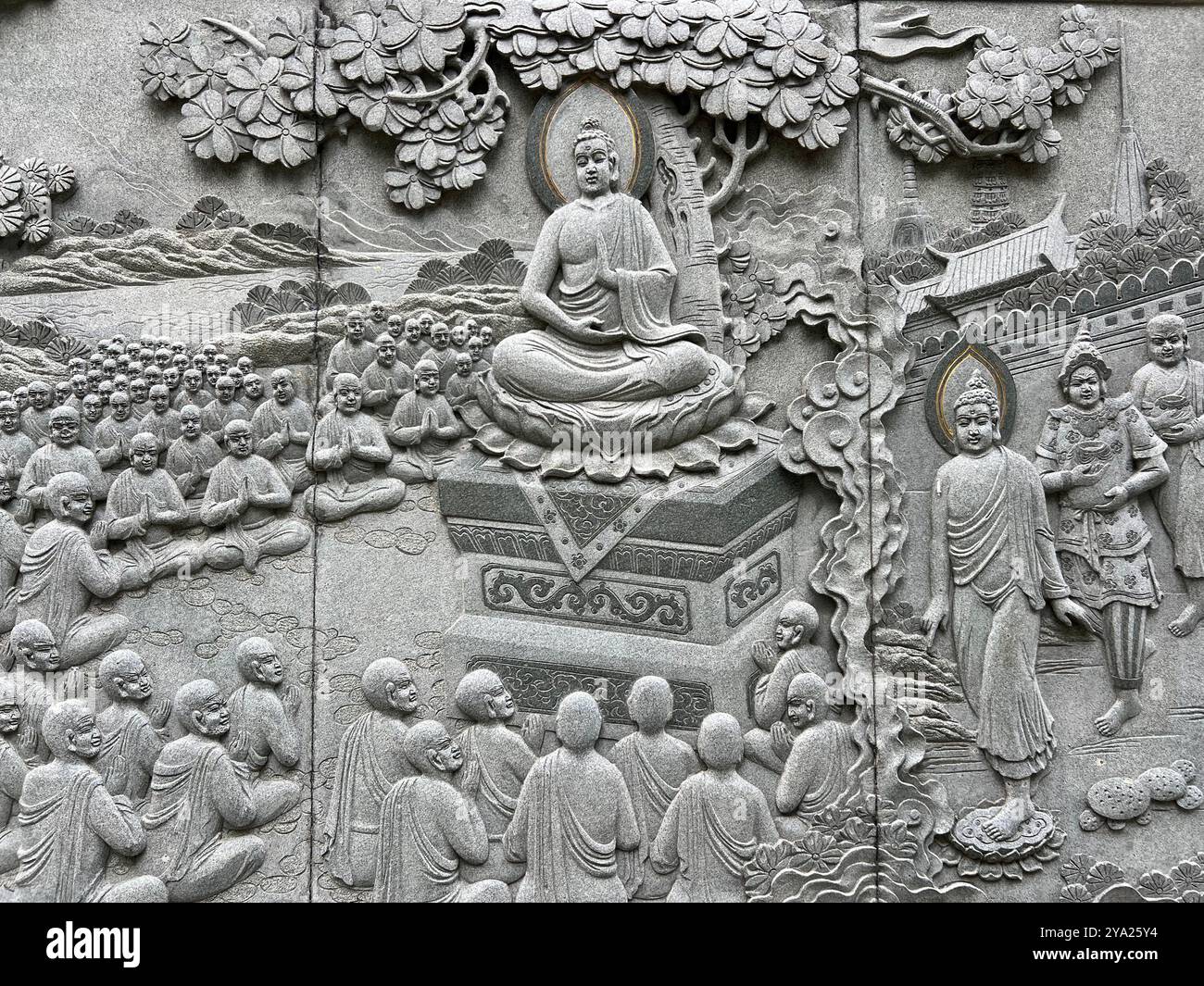 Una parete grigia scolpita, raffigurante il Buddha, seduto sotto l'albero di Bodhi, circondato dal suo discepolo o dai suoi monaci per imparare il modo del suo insegnamento. - Immagine stock catturata con smartphone