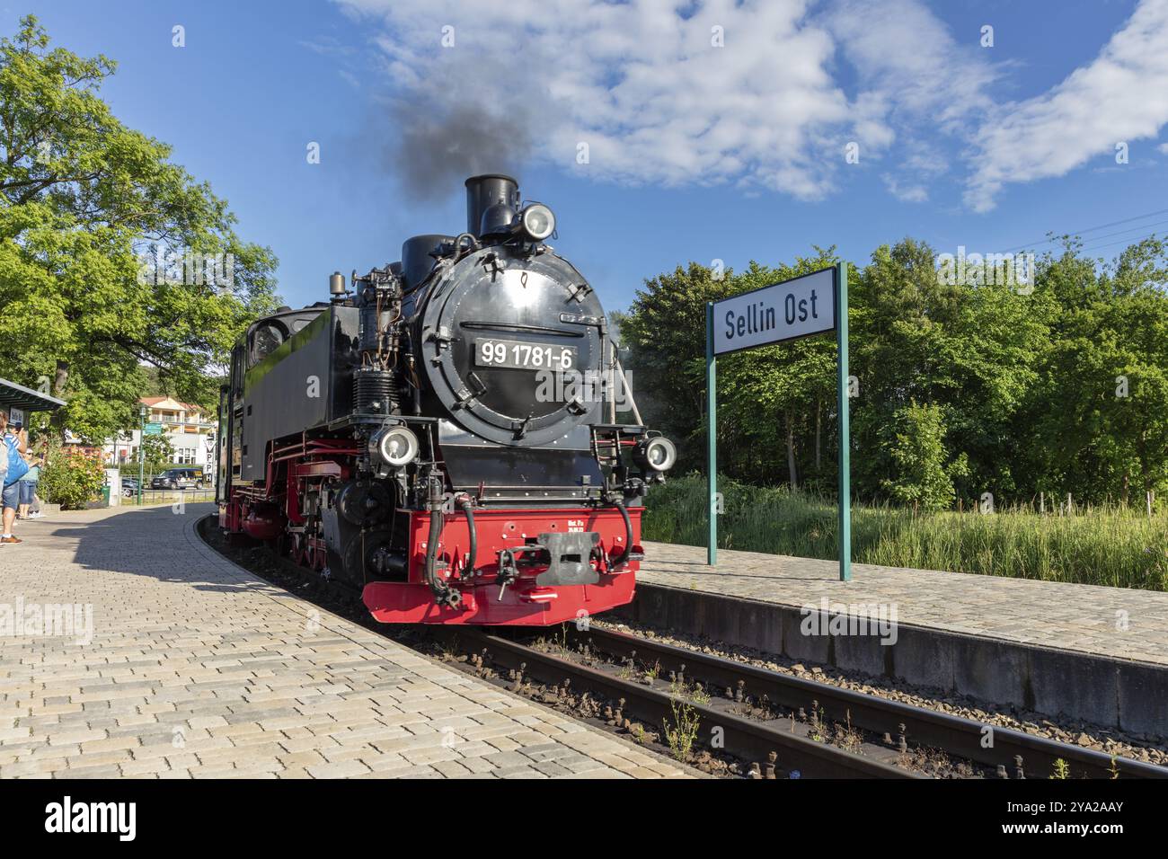 Una locomotiva a vapore si trova presso la stazione ferroviaria con un cartello in estate, Ruegen, Rasender Roland Foto Stock