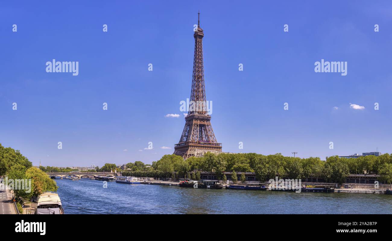 La Torre Eiffel da lontano con un fiume e cime verdi di alberi in una giornata di sole, Parigi Foto Stock