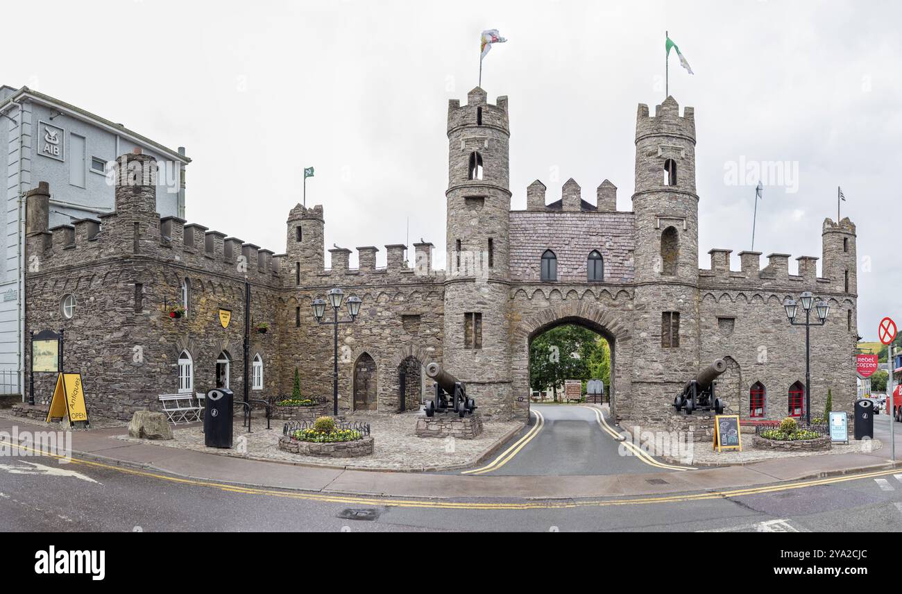 Imponente castello in pietra con bandiere e cannoni, personaggio storico all'angolo della strada, Macroom Foto Stock