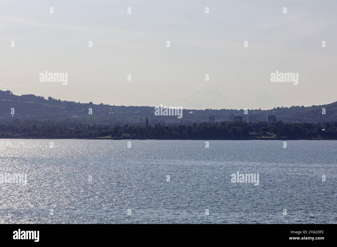 Ampio paesaggio collinare con alberi e un scintillante specchio d'acqua in primo piano, Belfast Foto Stock