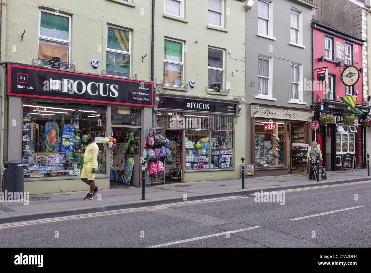 Vivace scena di strada con gente che cammina e negozi colorati lungo la strada, Tralee Foto Stock