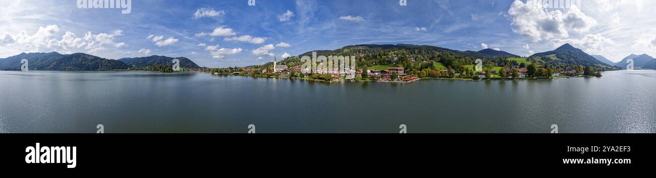 Vista panoramica del pittore su un villaggio bavarese su un lago, circondato da montagne sotto un cielo blu con nuvole, Schliersee Foto Stock