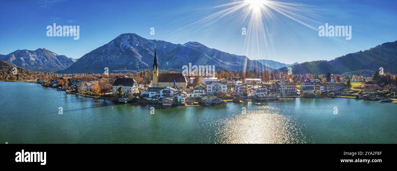 Foto panoramica di un villaggio sul lago con montagne sullo sfondo, il sole splende su un cielo blu limpido, Rottach-Egern Tegernsee Foto Stock