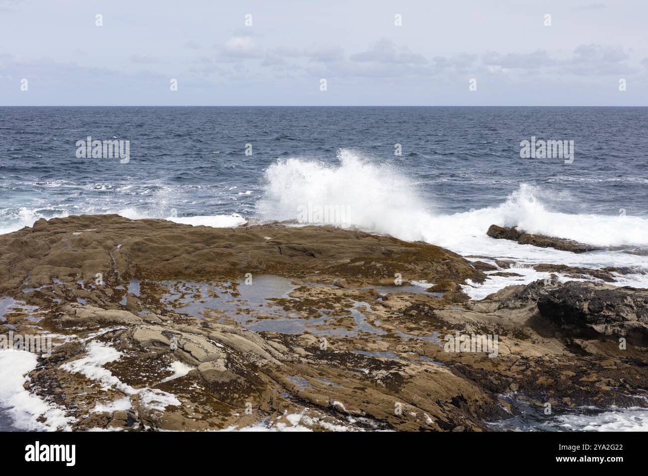 Paesaggio costiero con un'atmosfera tranquilla, le onde si incontrano con rocce piatte sotto un cielo limpido, Kilkee Foto Stock