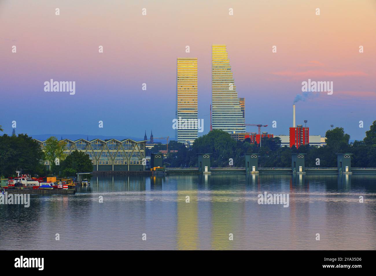 Due grattacieli si riflettono nell'acqua al tramonto. I dintorni mostrano aree verdi ed elementi industriali, Roche Towers, Hoffmann- la Roche, tal Foto Stock