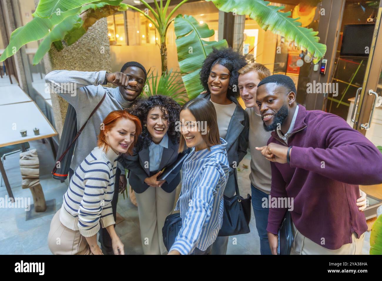 Gruppo di colleghi diversi che gestiscono e sorridono mentre scattano selfie insieme Foto Stock