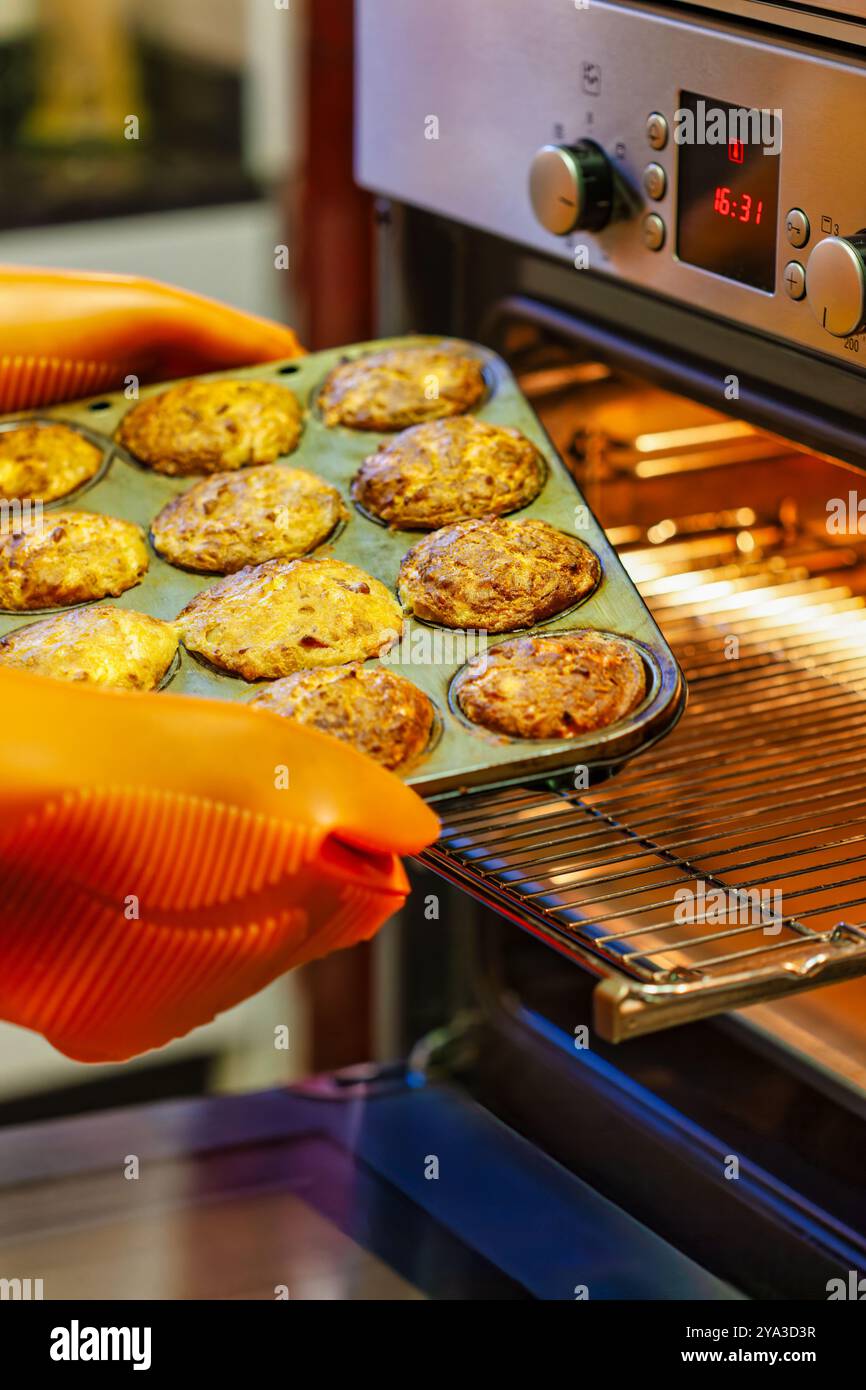 vassoio con muffin estratti dal forno con guanti protettivi in silicone Foto Stock